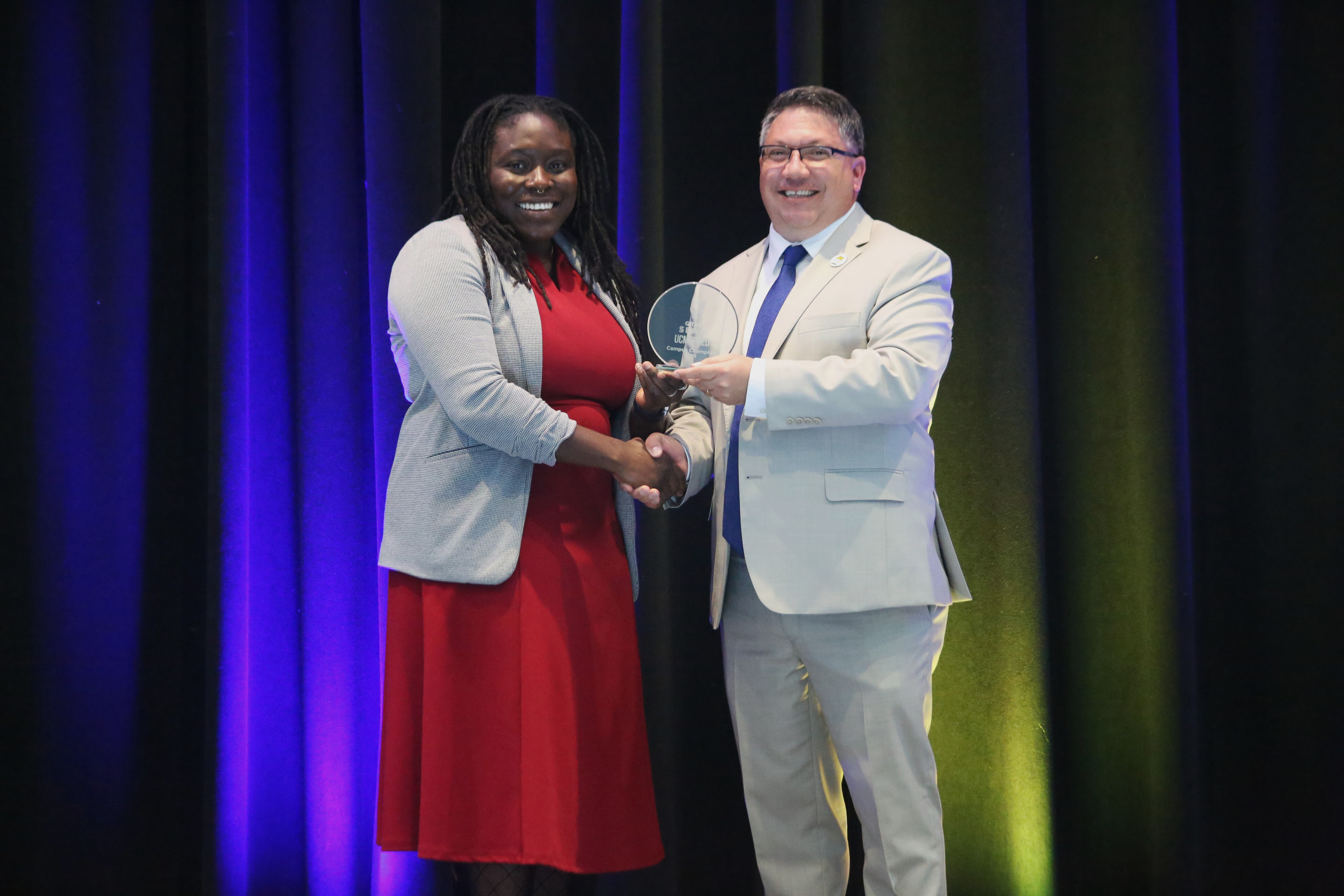 Grad Slam campus champion Tahirah Willams and Grad Dean Hrant Hratchian shaking hands on stage