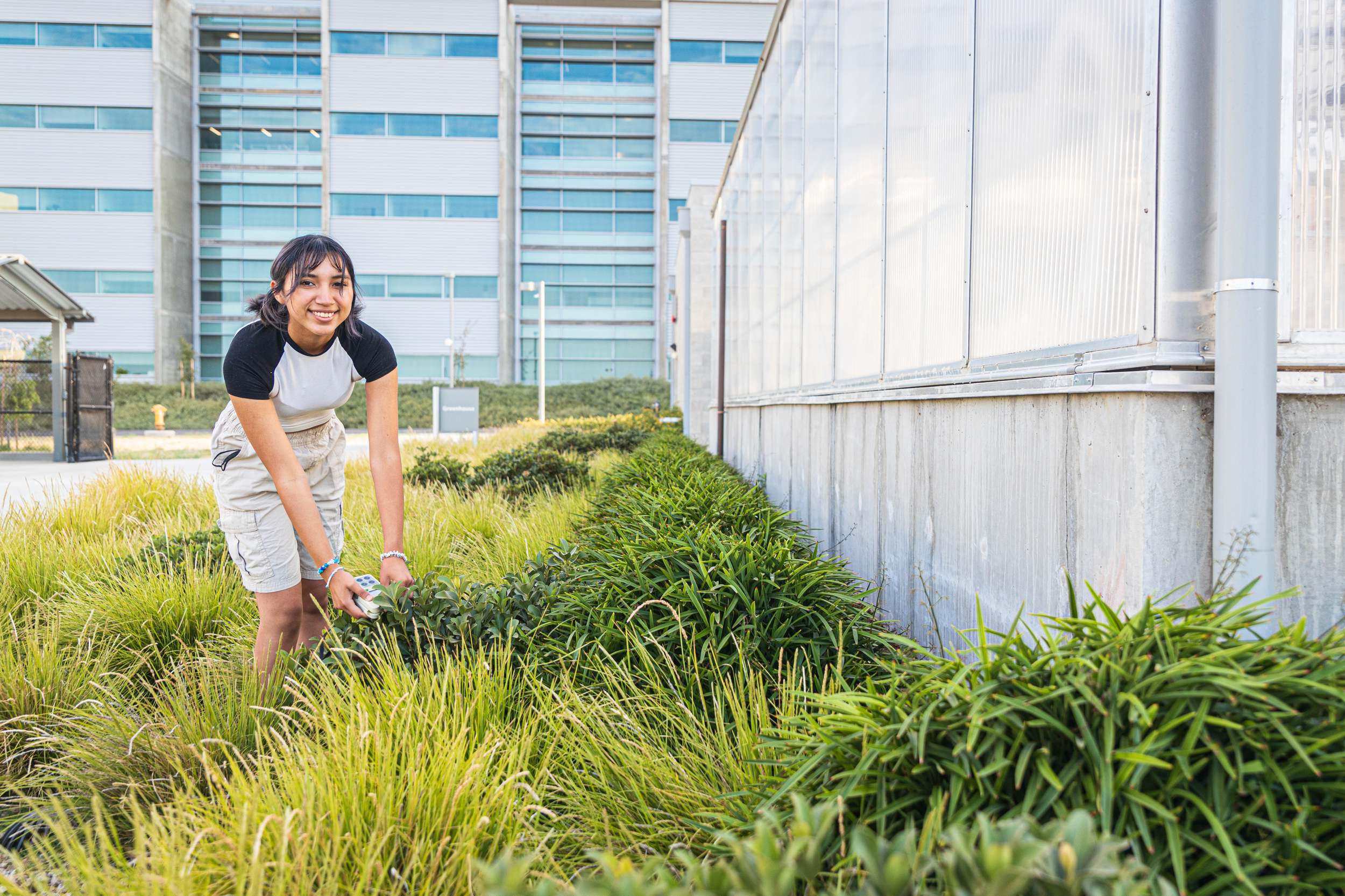 Person in grass standing next to a building.