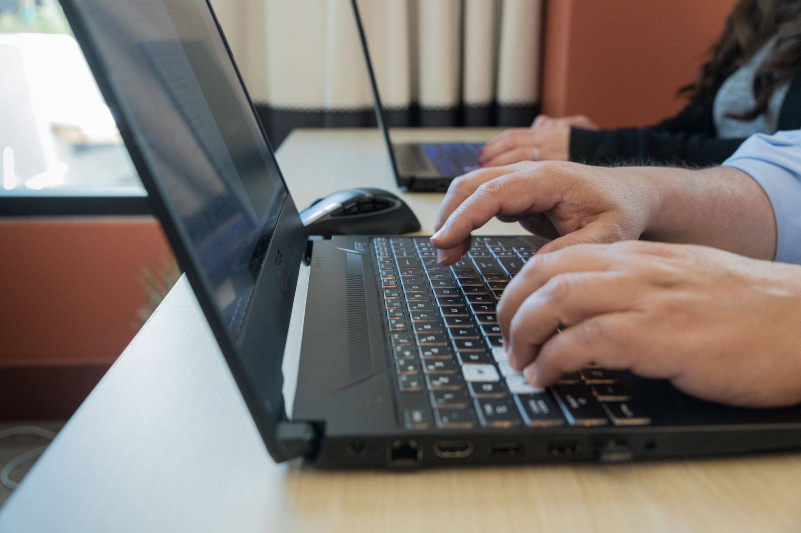Two people sitting at desks typing on laptops. 