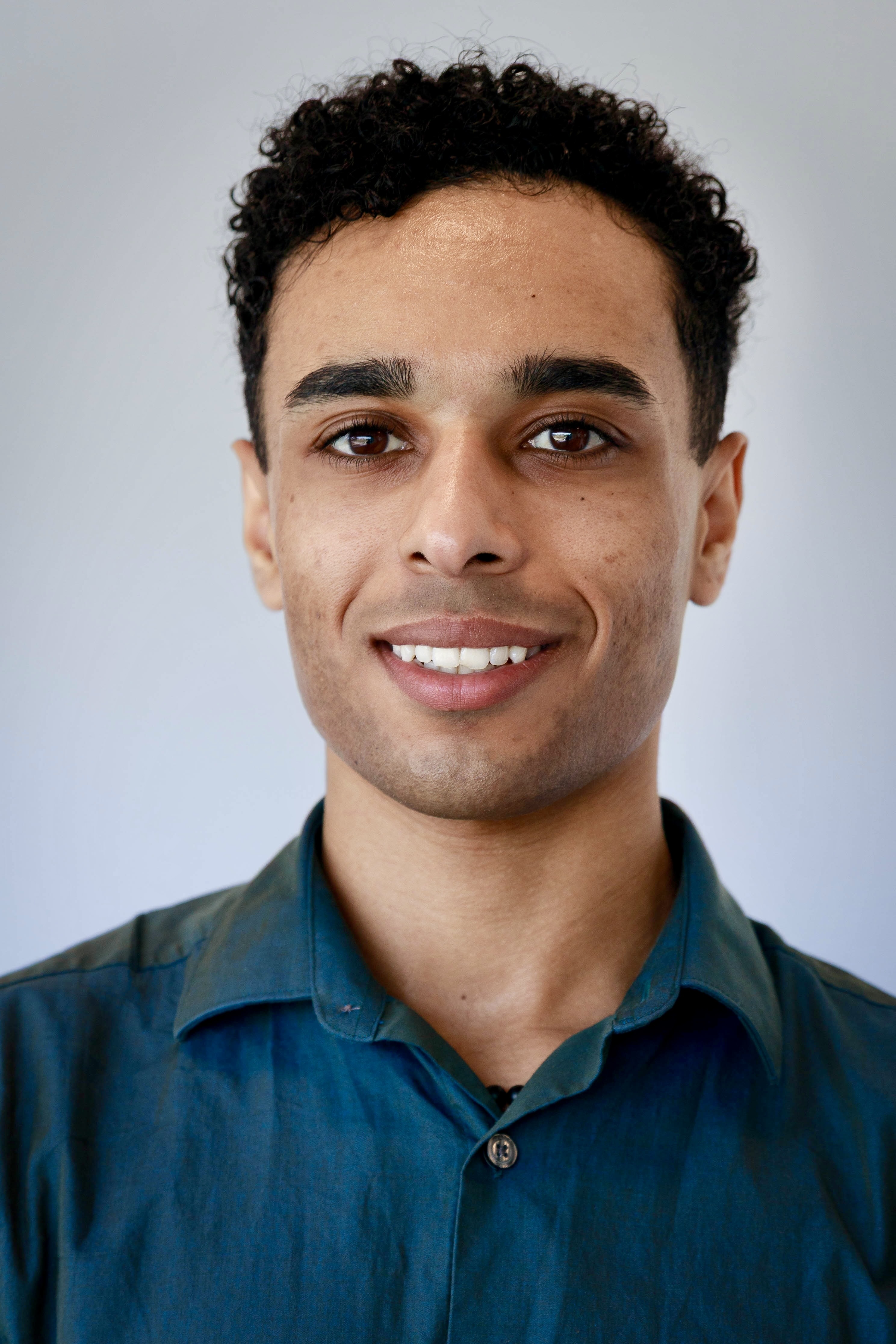 male with black hair wearing teal shirt