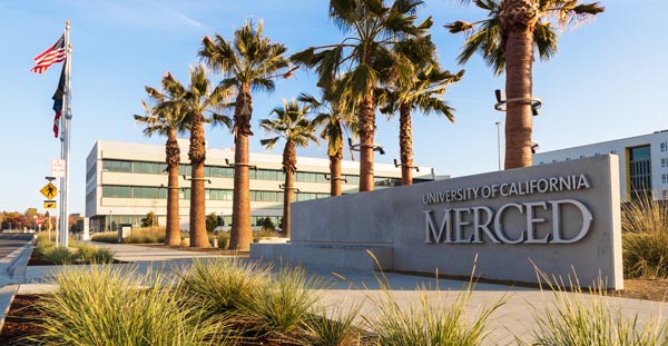 uc merced sign in front of campus near palm trees