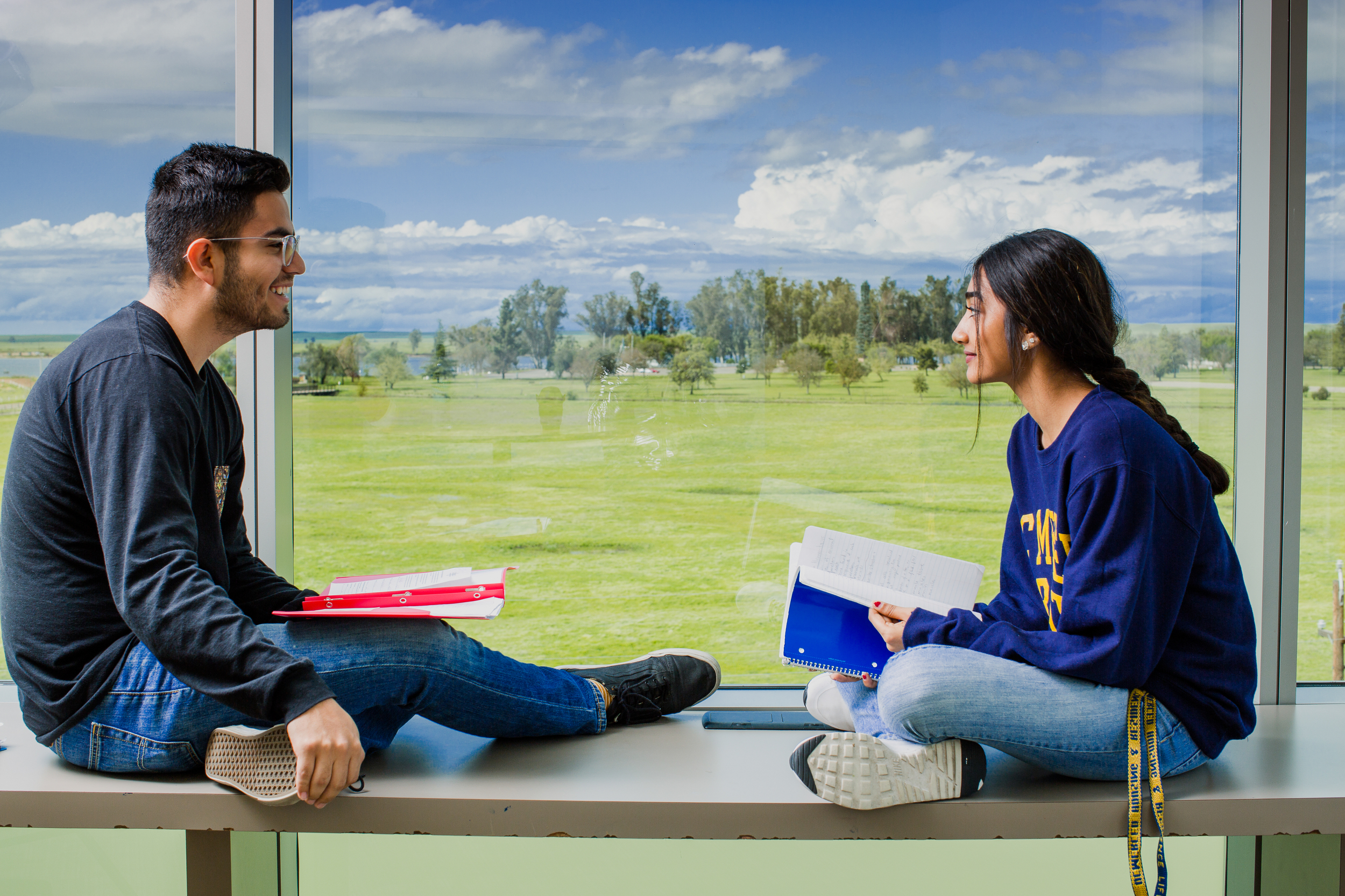 Two students sitting at a window studying