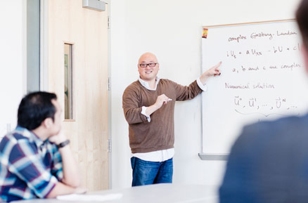 Professor Arnold Kim lecturing a class at the whiteboard