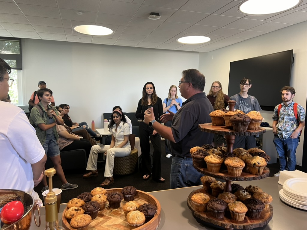 Group of grad students and grad dean sitting or standing around during an event