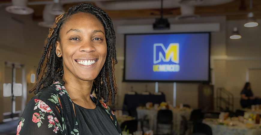 Ph.D. alumna Maxine Umeh-Garcia in conference room with screen in background