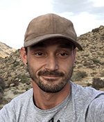 male wearing gray t shirt and tan baseball cap