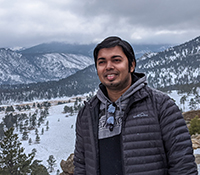 male wearing gray jacket near snow covered mountains