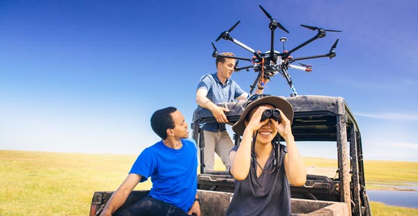 students with faculty member flying a drone on top of a golf cart