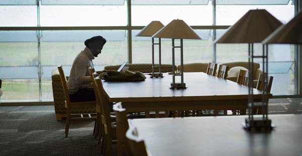 male student studying in the library at the table