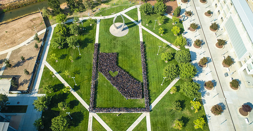 An aerial video of individuals clad in blue formed in the shape of California, with a heart in the middle.