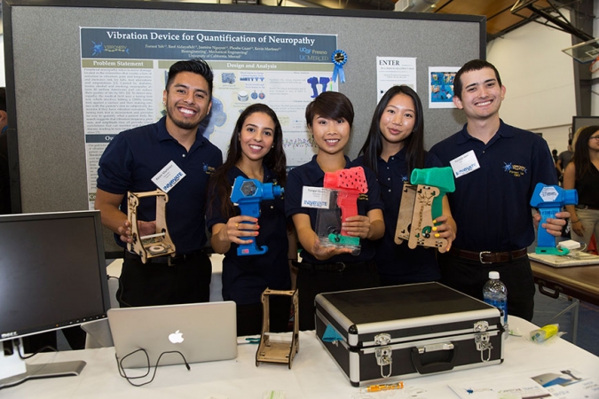 Five college student hold up electronic components they've invented